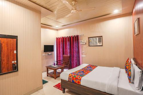 a bedroom with a bed and a chair and a table at FabHotel Limewood in Dehradun