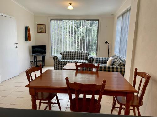 a living room with a wooden table and chairs at Peaches in Kingscote