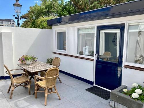 ein kleines Haus mit einem Tisch und Stühlen auf einer Terrasse in der Unterkunft Beachhouse Stranddistel 100m from the beach in Noordwijk aan Zee