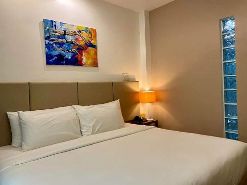 a bedroom with a white bed and a painting on the wall at Ciabel Hotel and Fitness Center in San Juan