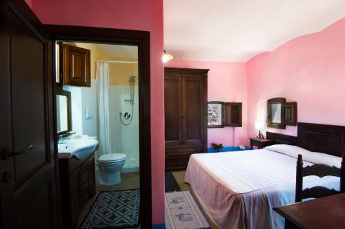 Habitación de color rosa con cama y lavamanos en Castello Malicas, en Galtellì