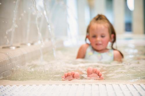a little girl swimming in a bathtub at Nykščio Namai & SPA in Anykščiai
