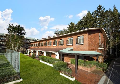 a brick building with a green lawn in front of it at The Gran Resort Elegante Karuizawa in Karuizawa