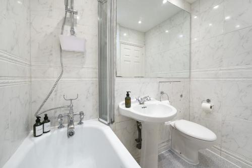 ein weißes Badezimmer mit einem Waschbecken, einer Badewanne und einem WC in der Unterkunft 2 Bedr, 3 Beds, 1 Bath Thames, Trafalgar SQ in London