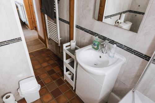 a bathroom with a sink and a mirror and a toilet at HILLSIDE COTTAGE - 3 bed property in North Wales opposite Adventure Park Snowdonia in Dolgarrog