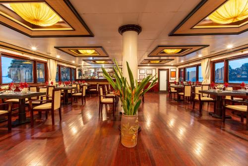 un restaurant avec des tables, des chaises et une plante dans l'établissement Swan Cruises Halong, à Hạ Long