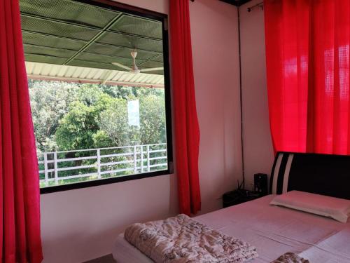 1 dormitorio con cortinas rojas y ventana en Kanva Farms, en Kotdwāra