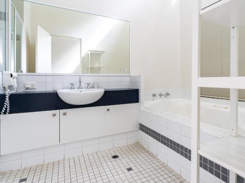 a white bathroom with a sink and a tub at Forestview Apartment Margaret River in Margaret River Town