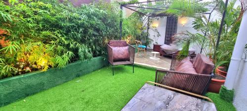 a garden with green grass and chairs and a table at Giovanni Suites in Bhopal