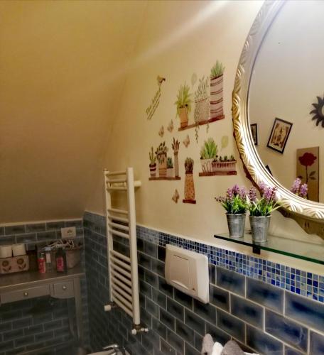a bathroom with a mirror and plants on the wall at Casolare Isabella "Il rifugio dei vinili" and Alice's room in Ponsacco