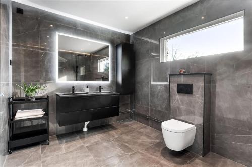 uma casa de banho com um lavatório, um WC e um espelho. em Luxurious & Cozy 2 Train Stops to City King Beds em Estocolmo