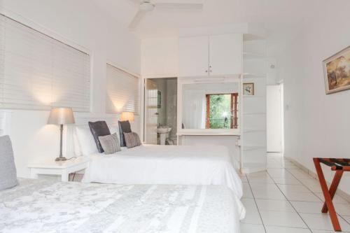 a white bedroom with two beds and a bathroom at Rivendell Bed and Breakfast in Hillcrest