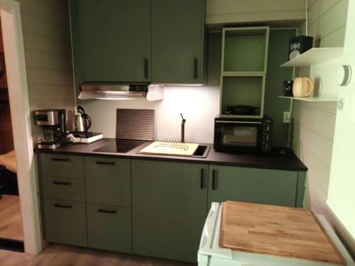 a kitchen with green cabinets and a counter top at Koselig leilighet , med parkering og ski in &out. in Oppdal