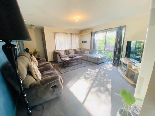 a living room with a couch and a tv at ENTIRE HOME IN WERRIBEE,BEST POSSIBLE LOCATION YOU CAN FIND in Werribee