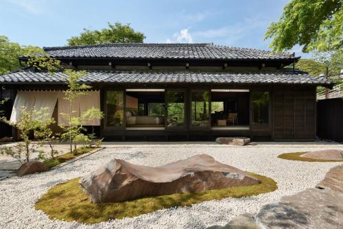 una casa con una gran roca en el patio delantero en LOQUAT西伊豆 en Izu