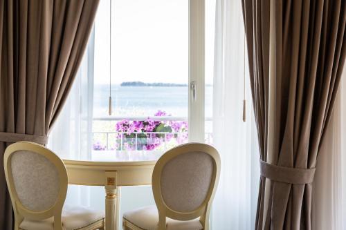 a table and two chairs in front of a window at Hotel Villa Florida & Suite Apartments in Gardone Riviera