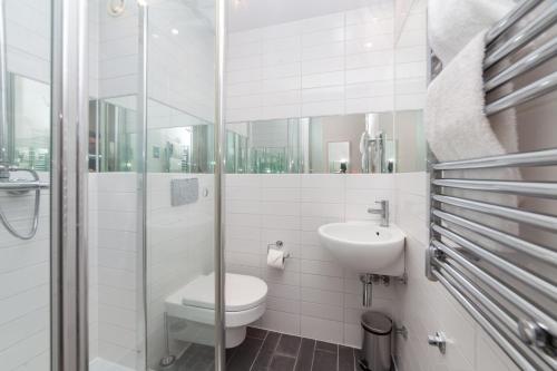 La salle de bains blanche est pourvue de toilettes et d'un lavabo. dans l'établissement Camden Prime ApartHotel, à Londres