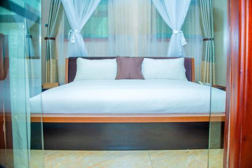 a bed with white sheets and pillows in a room at Hera Hotel Kampala in Kampala