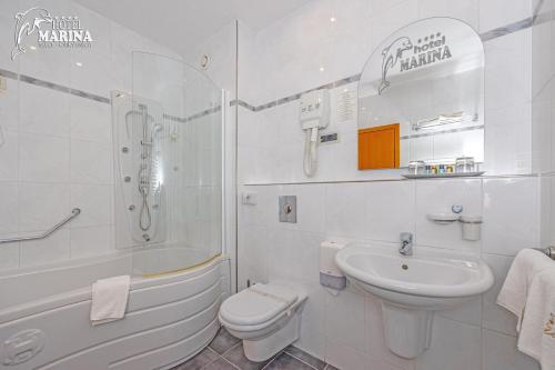 bagno bianco con vasca, lavabo e servizi igienici di Hotel Marina a Selce