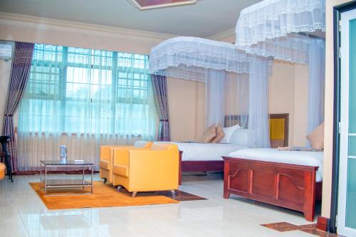 a bedroom with two beds and a couch and a table at Hera Hotel Kampala in Kampala