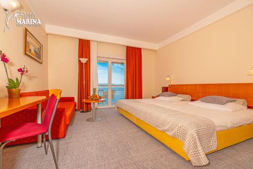 a hotel room with a bed and a desk and a window at Hotel Marina in Selce