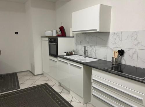 a kitchen with white cabinets and a black counter top at A.M.C. Ferienwohnung in Karlstadt