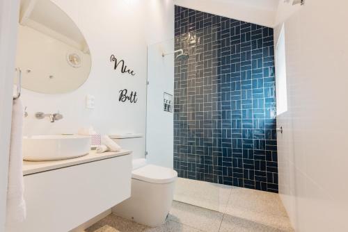 y baño con aseo y ducha de azulejos azules. en Port O' Call Motel, en Port Campbell