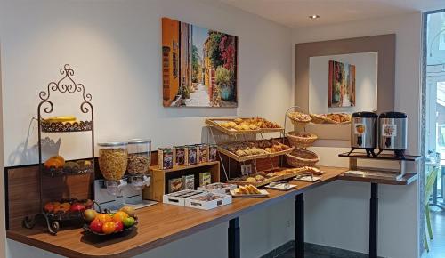 a bakery with a counter filled with different types of food at Hotel Le Majestic Canet plage in Canet-en-Roussillon
