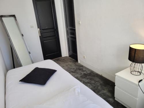 a bedroom with a white bed with a black pillow at Apt 6 du Temple 2 chambres & Parking in Cambrai