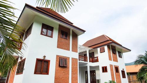 une maison blanche avec un toit marron dans l'établissement Baan Bhuwann Holiday Apartment, à Chaloklum