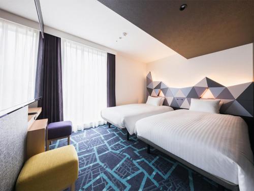 a hotel room with two beds and a chair at JR East Hotel Mets Premier Akihabara in Tokyo