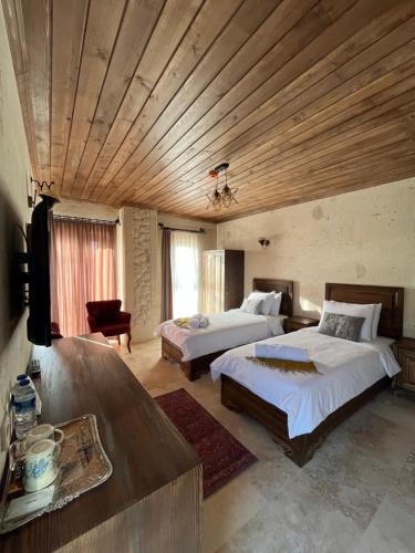 a bedroom with two beds and a flat screen tv at UCHI Cappadocia in Uchisar