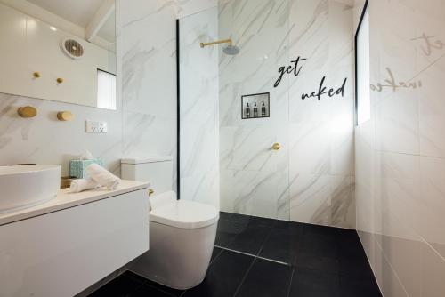 a white bathroom with a toilet and a shower at Port O' Call Motel in Port Campbell