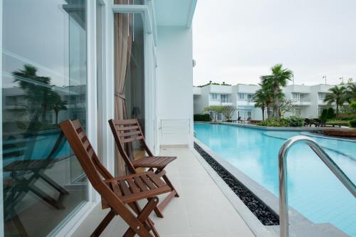 a balcony with two chairs and a swimming pool at Hua Hin One Bedroom One Bathroom with Pool Access Beachfront Nice Furniture in Ban Bo Fai