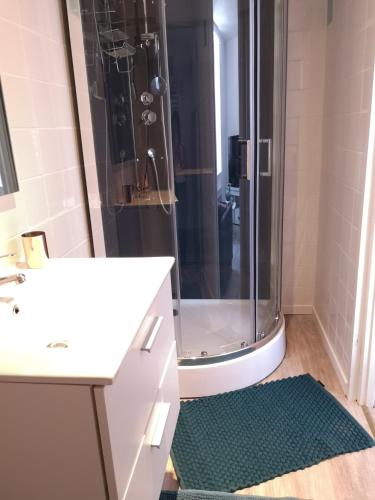 La salle de bains est pourvue d'une douche, d'un lavabo blanc et d'un comptoir. dans l'établissement Charmant logis dans une construction de caractère, à Gérardmer