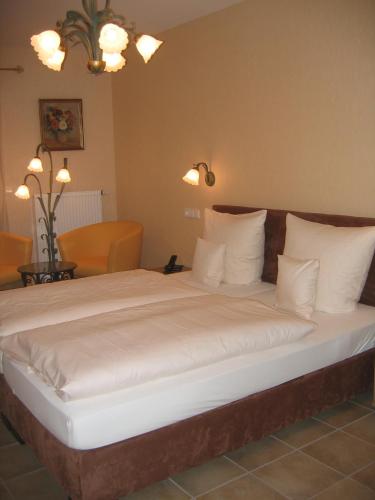 uma cama grande com almofadas brancas num quarto em Gästehaus Oswald em Forst