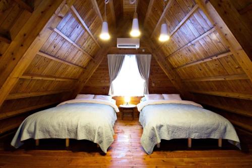 two beds in a attic room with a window at にらい恩納　杉の木 in Onna