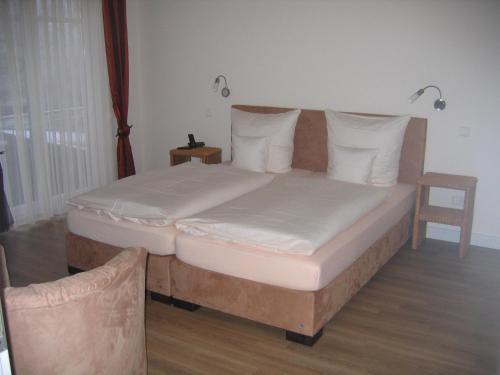 - un lit avec des draps et des oreillers blancs dans l'établissement Gästehaus Oswald, à Forst
