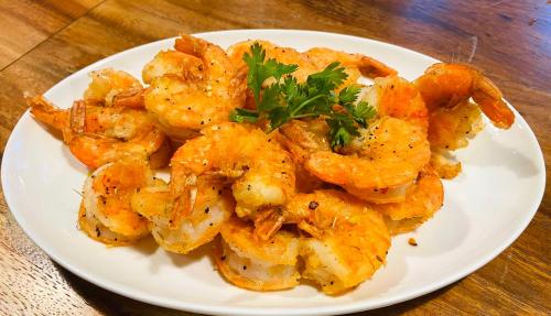 a white plate of shrimp on a wooden table at Patong Heights in Patong Beach