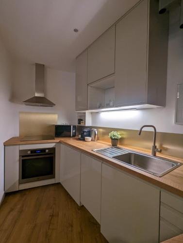 a kitchen with white cabinets and a stainless steel sink at Le 5 bis, une maison de ville dans le centre historique in Saint-Galmier