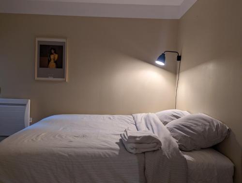 a bedroom with a bed with white sheets and a lamp at Le 5 bis, une maison de ville dans le centre historique in Saint-Galmier