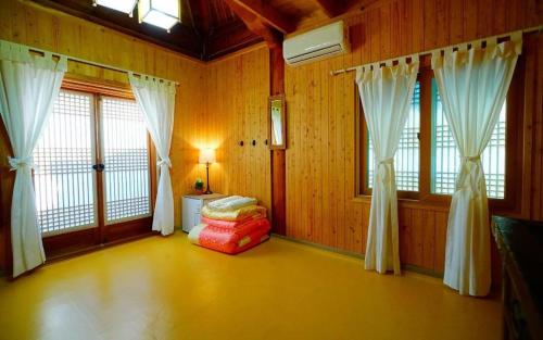 a room with wooden walls and windows and a chair at Full of Love Guesthouse in Jeonju