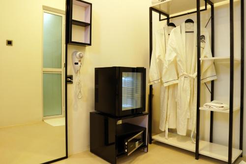 uma televisão numa bancada num quarto com roupas em MOONSHELL RESIDENCE em Baa Atoll