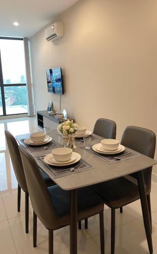 a dining room with a table with chairs and a television at Atria Sofo Suites - Petaling Jaya in Petaling Jaya