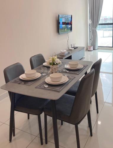 a dining room table with chairs and plates and a television at Atria Sofo Suites - Petaling Jaya in Petaling Jaya