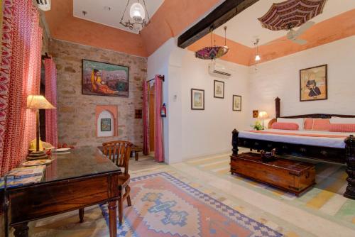 a bedroom with a bed and a desk in a room at Fort Dadhikar, Alwar in Alwar