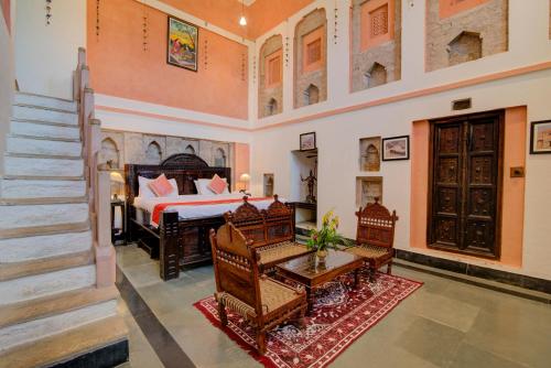 a bedroom with a bed and a table and chairs at Fort Dadhikar, Alwar in Alwar