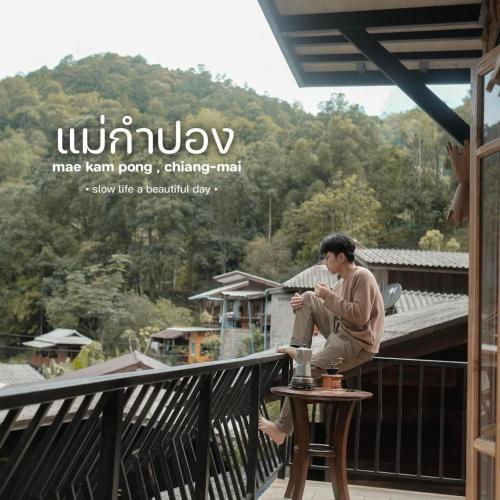 a man sitting on a table on a balcony at ไชยพล โฮมสเตย์ หมู่บ้านแม่กำปอง in Ban Pok Nai