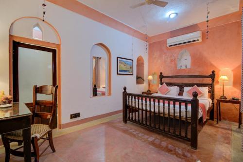 a bedroom with a bed and a desk and a chair at Fort Dadhikar, Alwar in Alwar