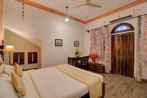 a bedroom with a bed and a desk and a window at Fort Dadhikar, Alwar in Alwar